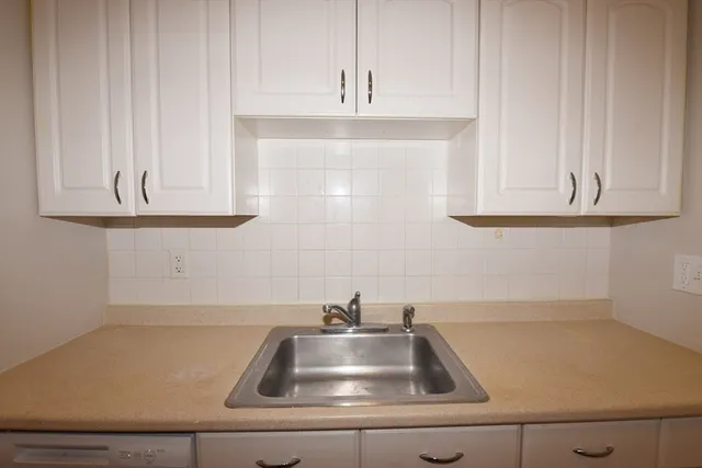a kitchen with granite countertop white cabinets and a sink