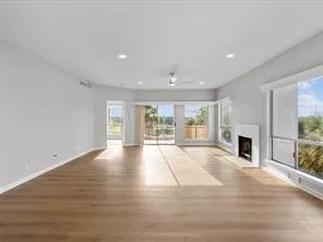 a view of an empty room with fireplace and wooden floor