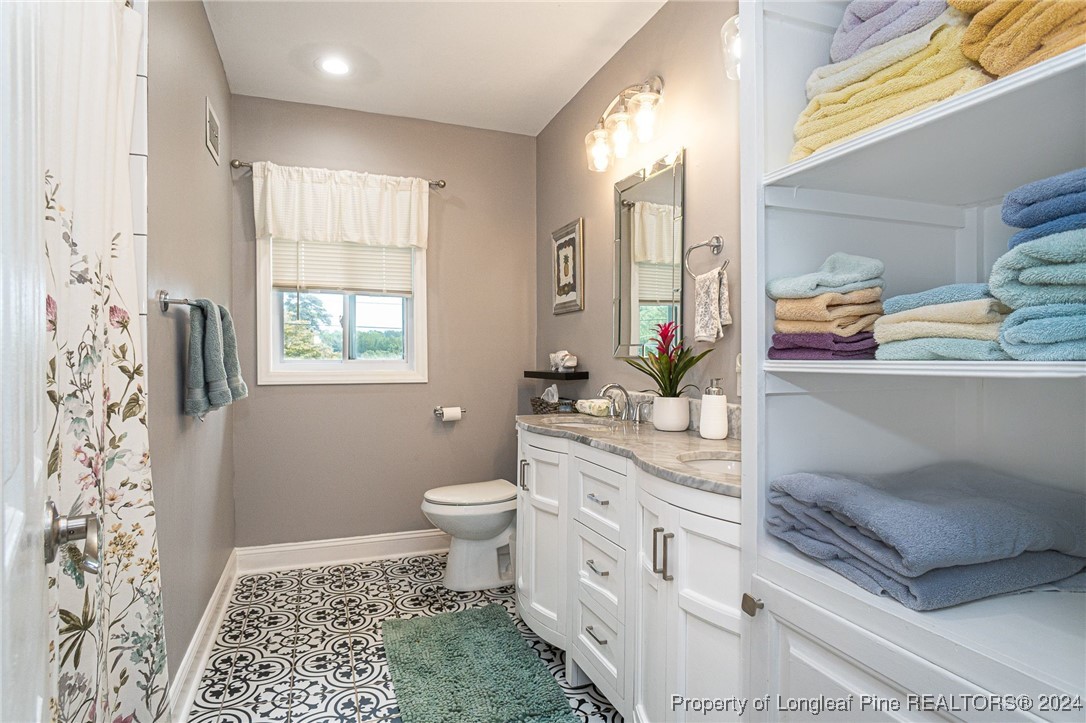 2539 Huntington Road Fayetteville, NC 28303 - Photo 27 of 39 a bathroom with a granite countertop sink a toilet and a shower