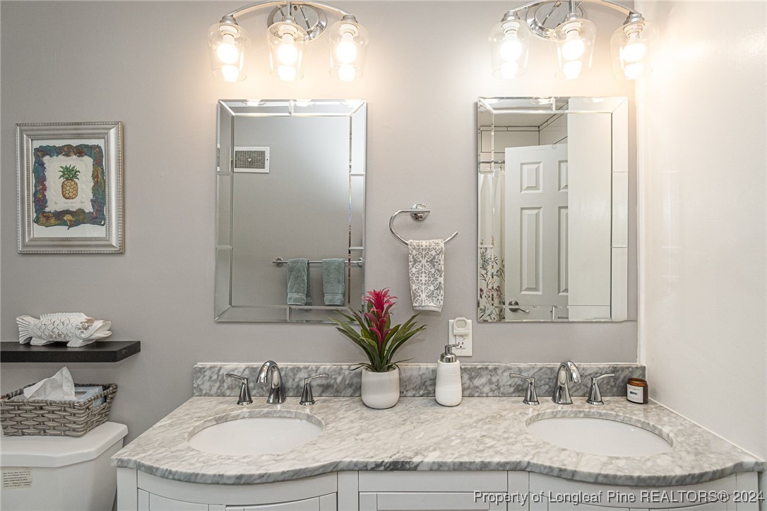 2539 Huntington Road Fayetteville, NC 28303 - Photo 28 of 39 a bathroom with a granite countertop sink a toilet and mirror