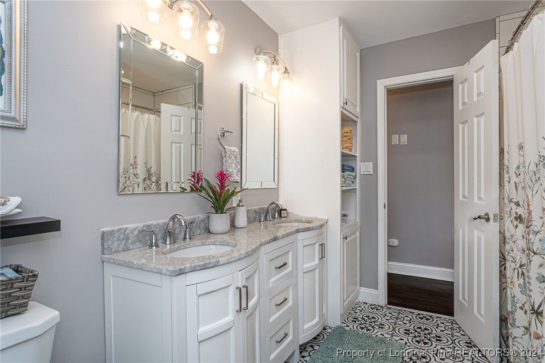 2539 Huntington Road Fayetteville, NC 28303 - Photo 29 of 39 a bathroom with a granite countertop sink a toilet and shower