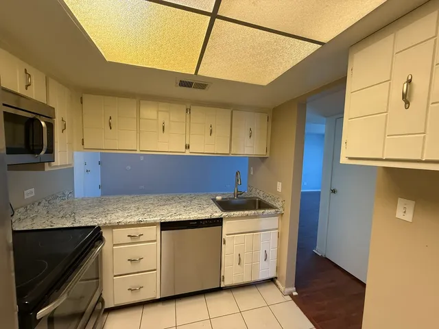 a kitchen with granite countertop white cabinets stainless steel appliances and a counter space