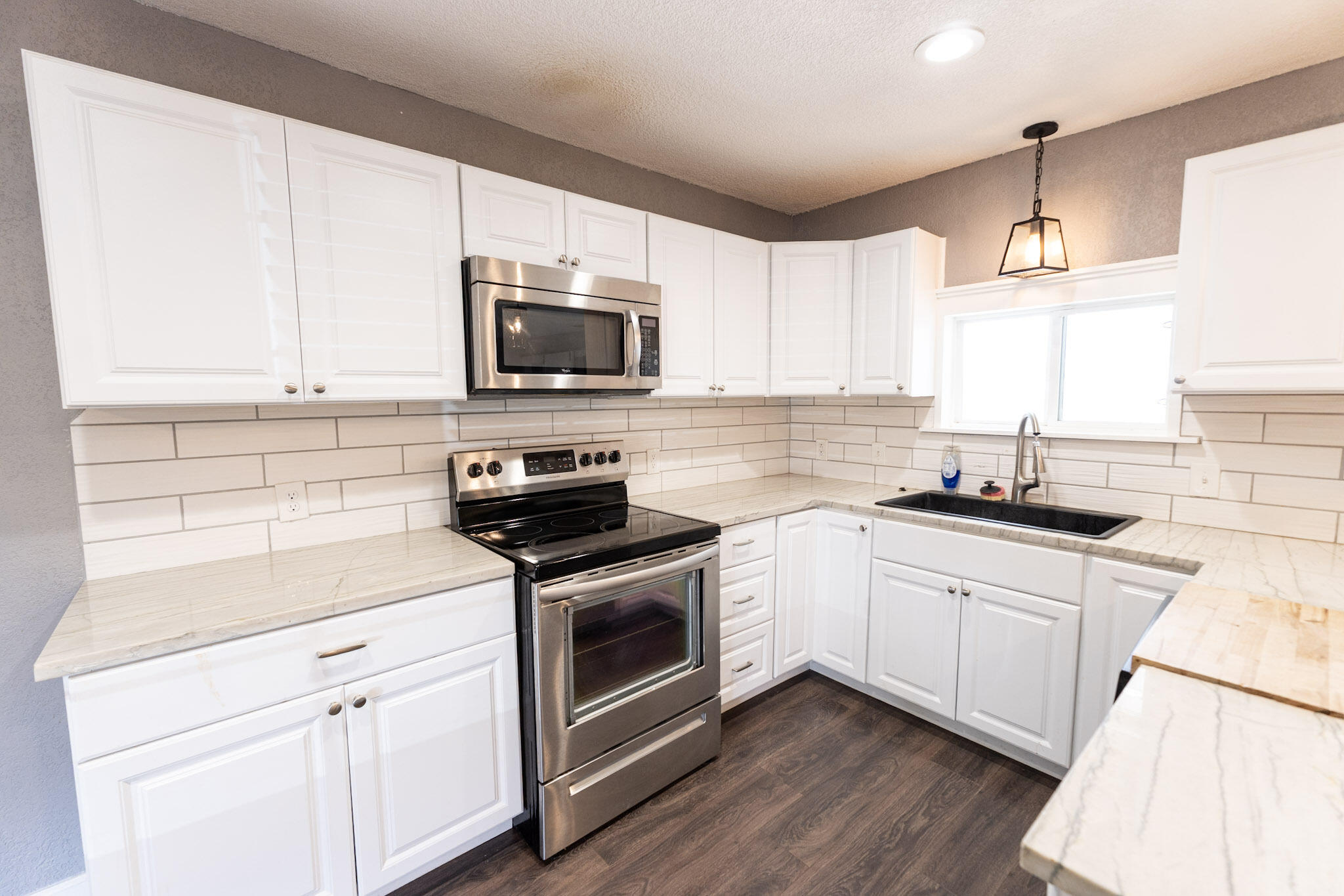 3006 36th Street Lubbock, TX 79413 - Photo 7 of 16 a kitchen with granite countertop white cabinets white stainless steel appliances and a sink