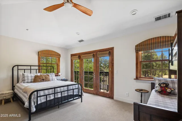 a bedroom with a bed a table and windows