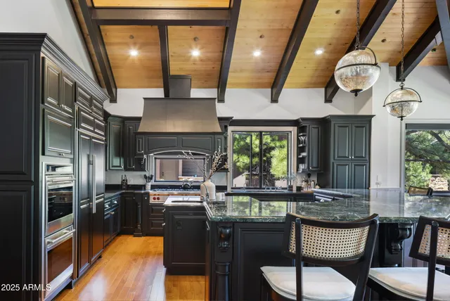 a kitchen with stainless steel appliances granite countertop a stove a sink dishwasher a dining table and chairs with wooden floor