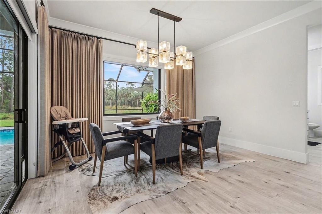 1720 21st Street Southwest Naples, FL 34117 - Photo 11 of 42 Dining space with ornamental molding, light wood-style flooring, and a chandelier
