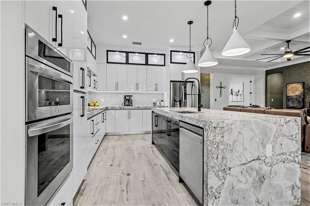 1720 21st Street Southwest Naples, FL 34117 - Photo 13 of 42 Kitchen with white cabinets, modern cabinets, light stone counters, coffered ceiling, and decorative light fixtures