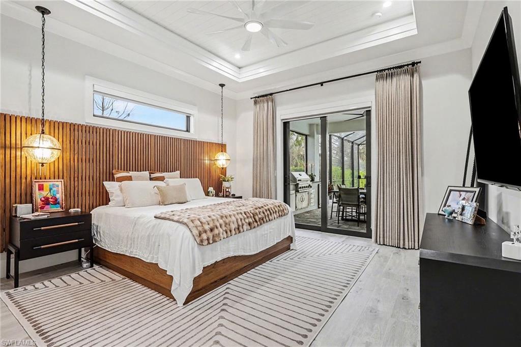 1720 21st Street Southwest Naples, FL 34117 - Photo 16 of 42 Bedroom with wooden walls, access to outside, ceiling fan, a raised ceiling, and light wood finished floors