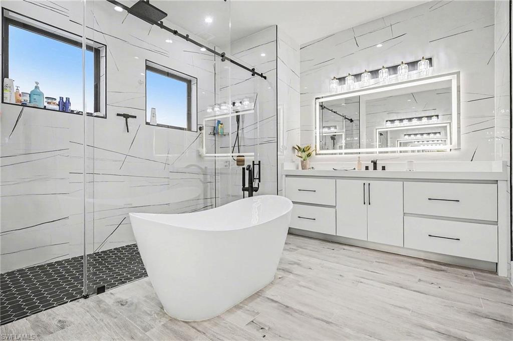 1720 21st Street Southwest Naples, FL 34117 - Photo 20 of 42 Bathroom with vanity, a soaking tub, a marble finish shower, and light wood-style floors