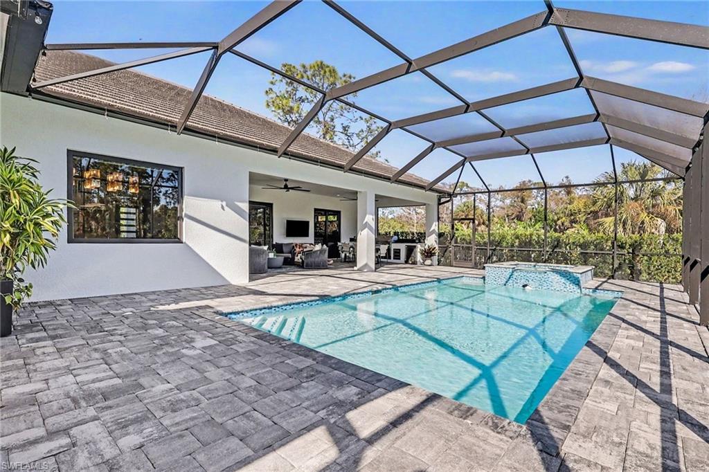 1720 21st Street Southwest Naples, FL 34117 - Photo 34 of 42 View of swimming pool featuring a lanai, a patio, a sunroom, a pool with connected hot tub, and outdoor lounge area
