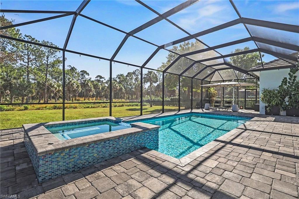1720 21st Street Southwest Naples, FL 34117 - Photo 35 of 42 View of pool featuring a sunroom, a patio area, a pool with connected hot tub, glass enclosure, and a lawn