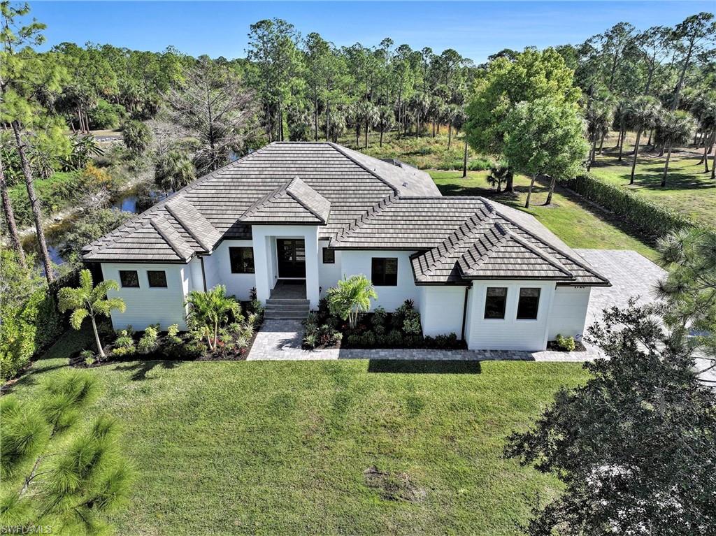 1720 21st Street Southwest Naples, FL 34117 - Photo 36 of 42 View of front facade featuring a front yard, a tiled roof, stucco siding, and view of wooded area