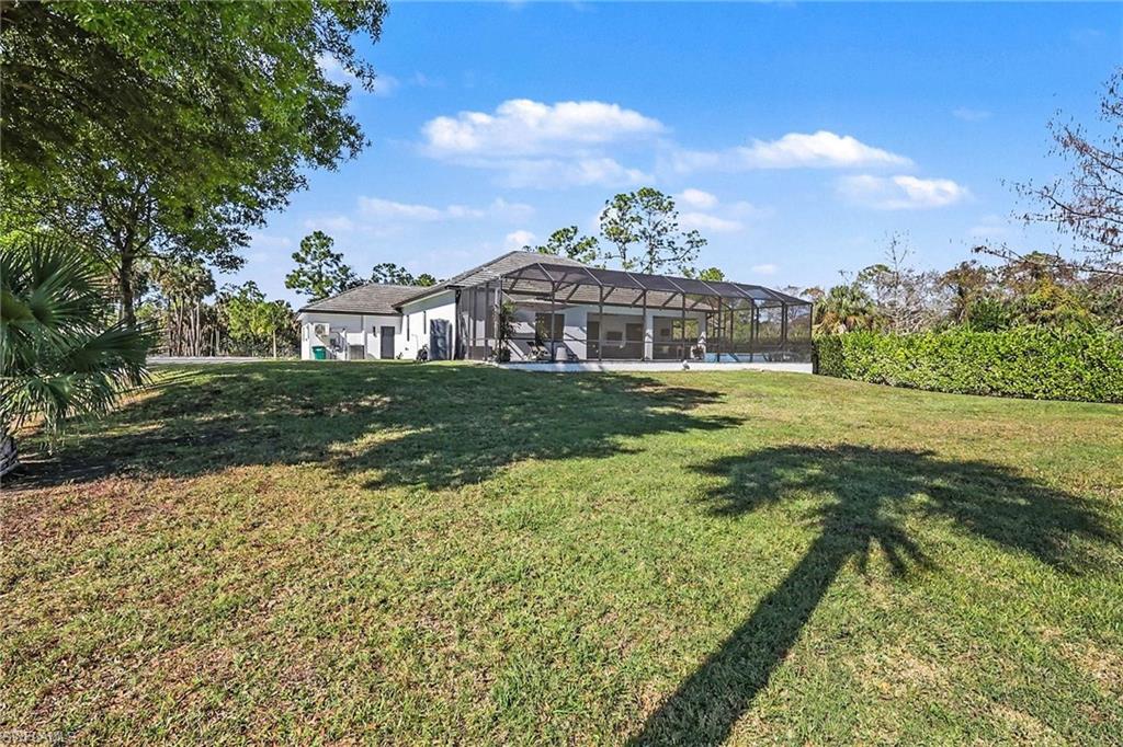 1720 21st Street Southwest Naples, FL 34117 - Photo 37 of 42 View of green lawn featuring a sunroom and glass enclosure
