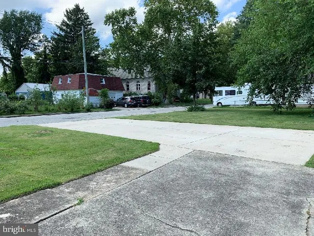 a front view of a house with a yard and a large tree