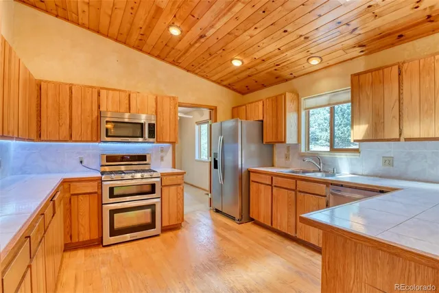 a kitchen with stainless steel appliances kitchen island granite countertop a stove a sink dishwasher and a refrigerator