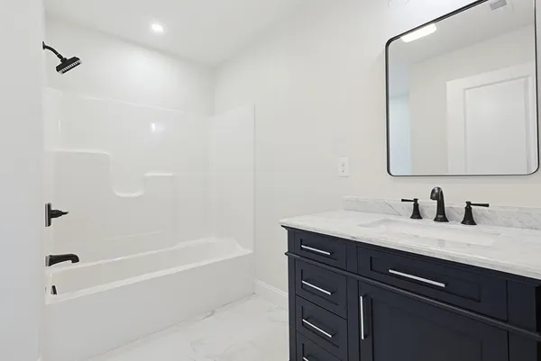 a bathroom with a granite countertop sink a mirror and a bathtub