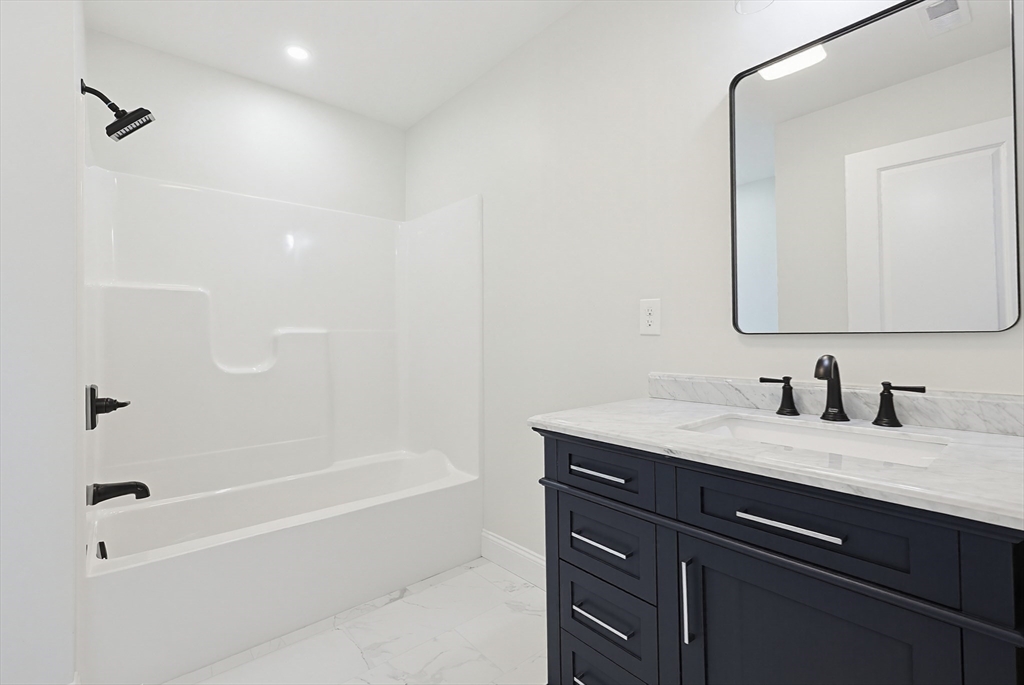 673 Pleasant Street Leicester, MA 01542 - Photo 24 of 38 a bathroom with a granite countertop sink a mirror and a bathtub