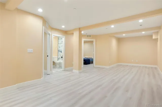 a view of an empty room with wooden floor and a bathroom