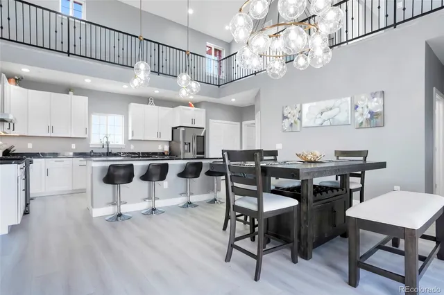 a kitchen with cabinets a sink dishwasher a dining table and chairs with wooden floor