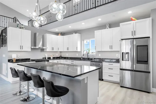 a kitchen with stainless steel appliances granite countertop a sink a stove a refrigerator cabinets and chairs