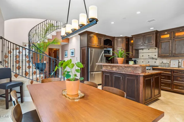 a kitchen with stainless steel appliances granite countertop a kitchen island a stove a dining table and chairs