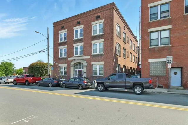 a front view of a building with cars parked