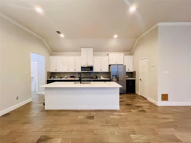 a living room with stainless steel appliances kitchen island granite countertop a refrigerator and a stove top oven