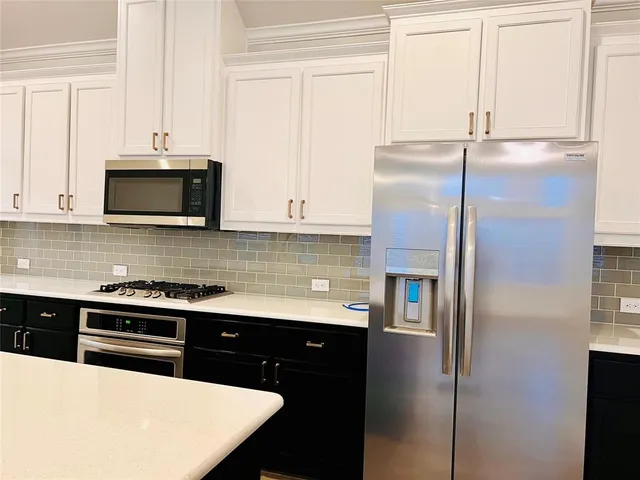 a kitchen with stainless steel appliances white cabinets and a refrigerator