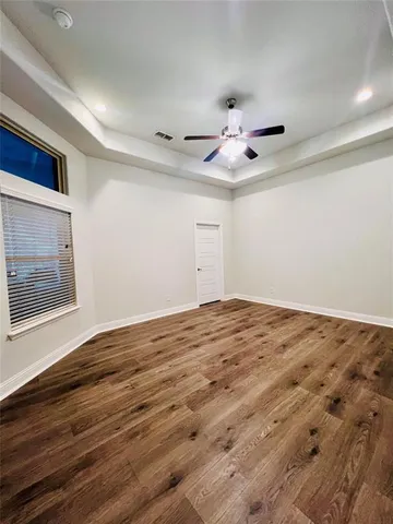 a view of empty room with wooden floor and fan