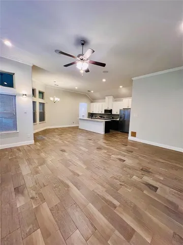 a view of an empty room with kitchen and a window