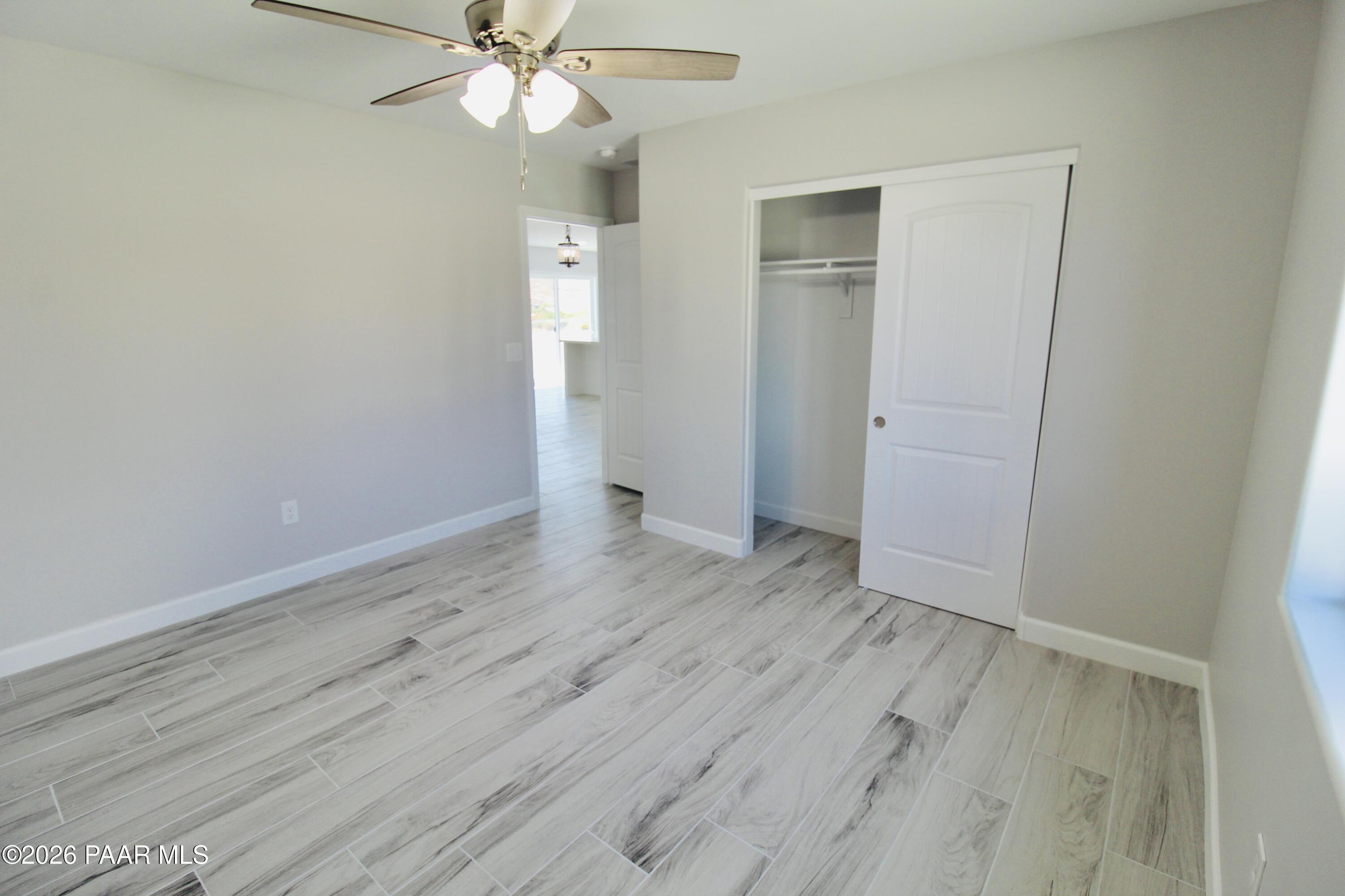 20275 East Mesa Verde Road Mayer, AZ 86333 - Photo 14 of 34 an empty room with wooden floor and fan