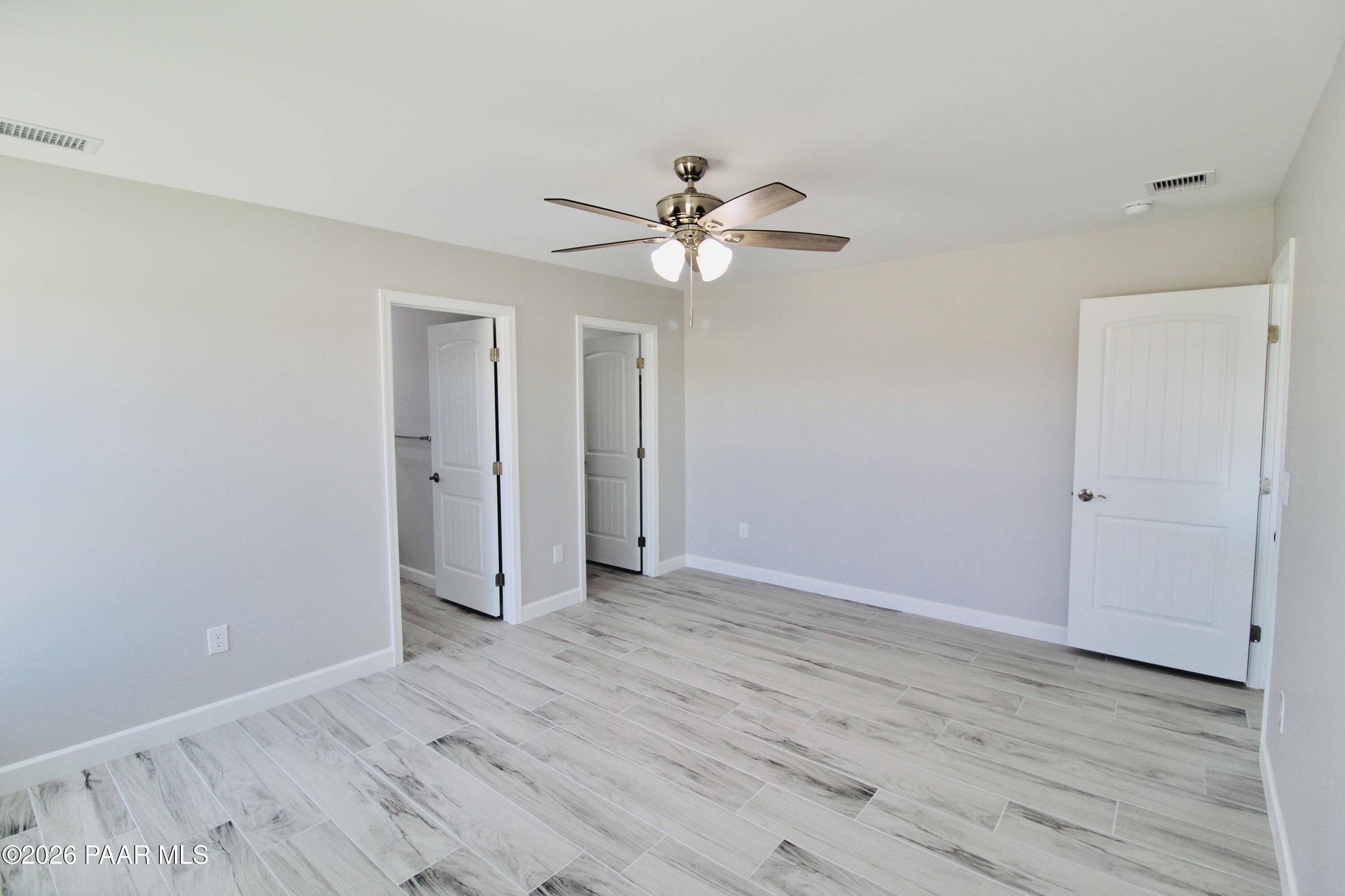 20275 East Mesa Verde Road Mayer, AZ 86333 - Photo 22 of 34 an empty room with wooden floor and fan