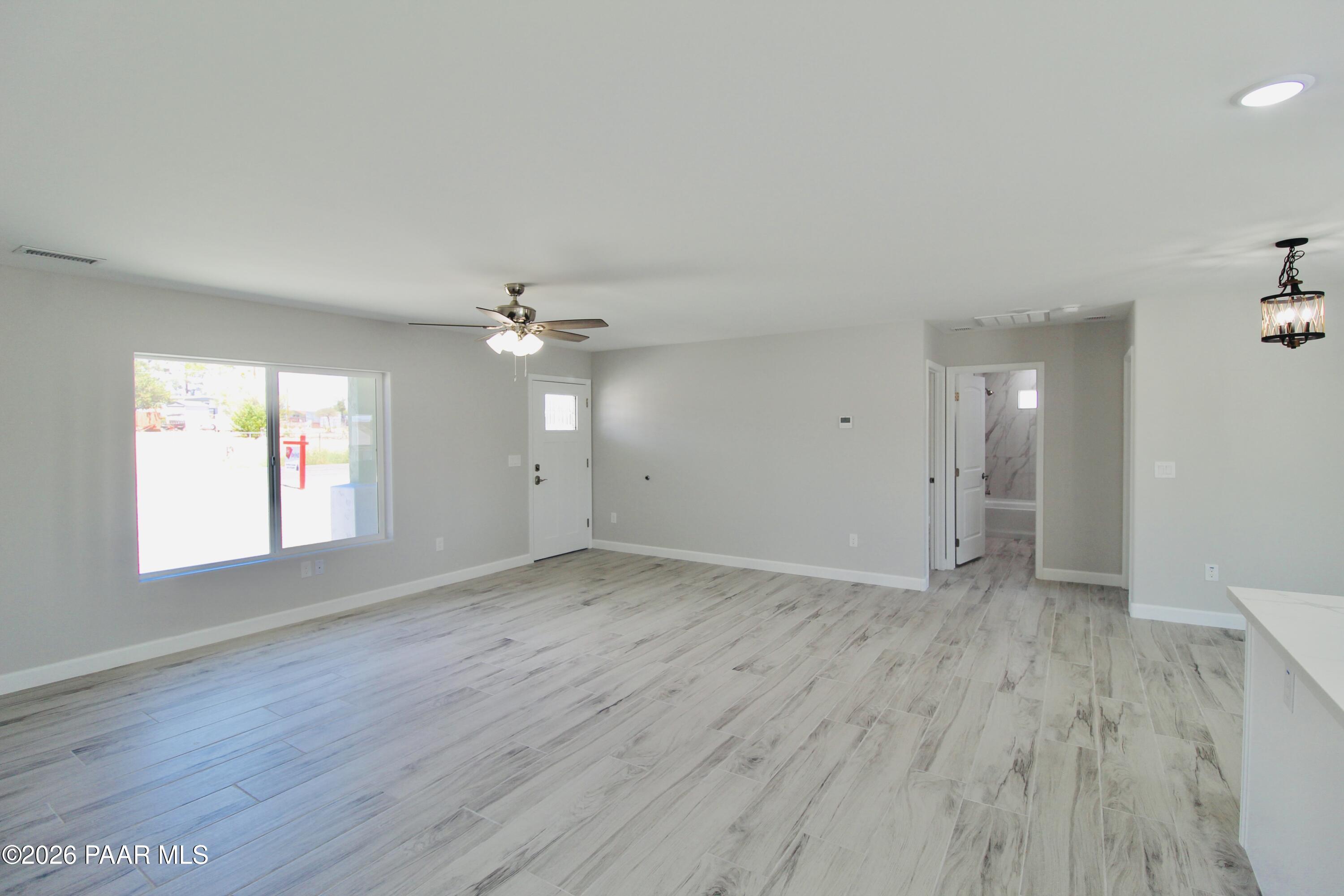20275 East Mesa Verde Road Mayer, AZ 86333 - Photo 5 of 34 an empty room with wooden floor ceiling fan and windows