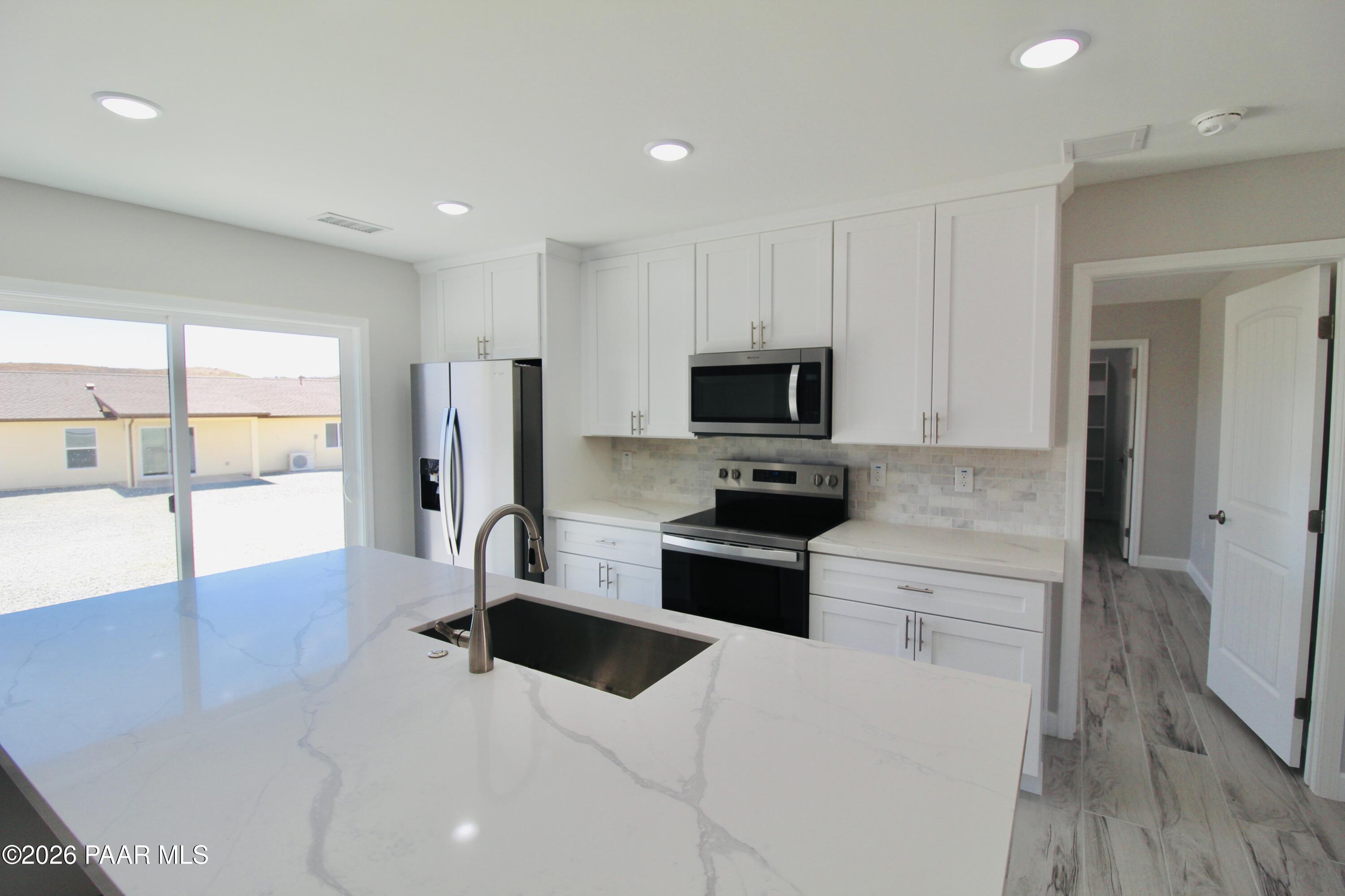 20275 East Mesa Verde Road Mayer, AZ 86333 - Photo 6 of 34 a large kitchen with stainless steel appliances a large counter top a stove a microwave a sink and a refrigerator