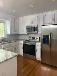 a kitchen with granite countertop a refrigerator stove and microwave