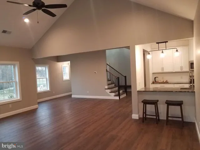 a view of an empty room and wooden floor and a kitchen