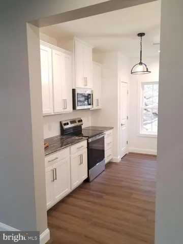 a kitchen with stainless steel appliances granite countertop a sink cabinets and wooden floor
