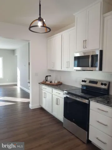 a kitchen with granite countertop a stove a sink and a microwave