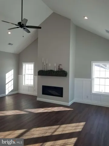 an empty room with wooden floor fireplace and windows