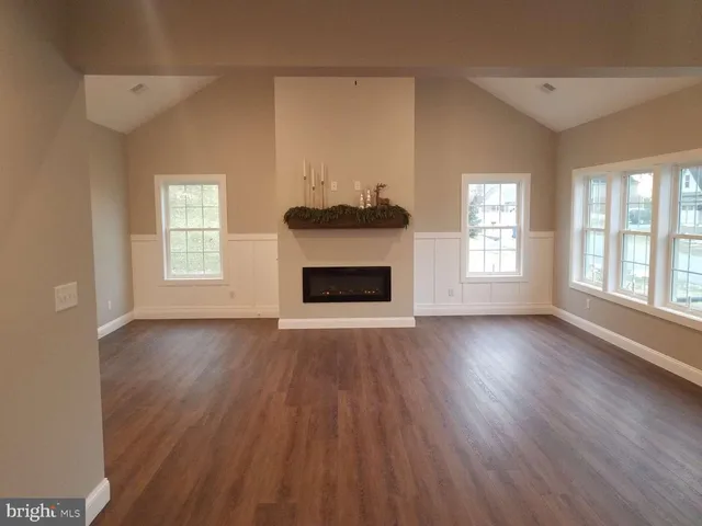 an empty room with wooden floor fireplace and windows