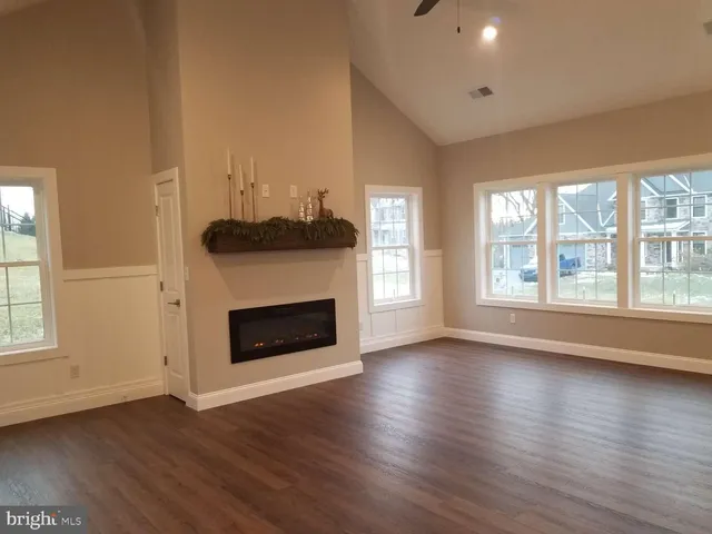 an empty room with wooden floor fireplace and windows