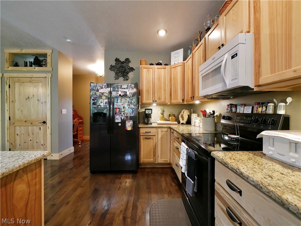75450 Fair Road Freeport, OH 43973 - Photo 11 of 45 Kitchen with dark hardwood / wood-style floors, range with electric stovetop, light stone counters, and black refrigerator with ice dispenser