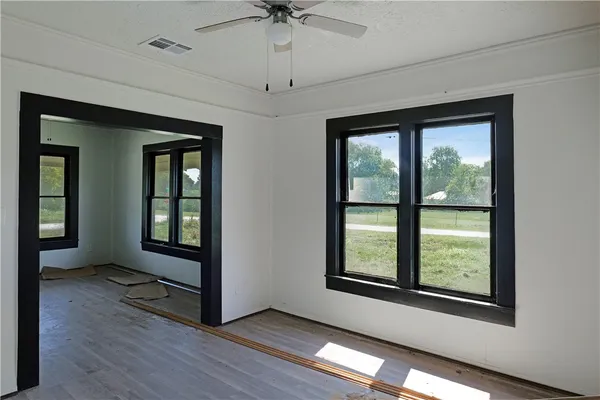 a view of an empty room with a window and wooden floor