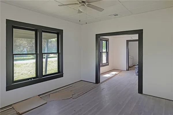 a view of an empty room with a window and wooden floor
