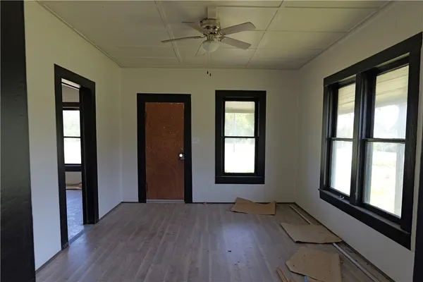 a view of empty room with wooden floor and fan