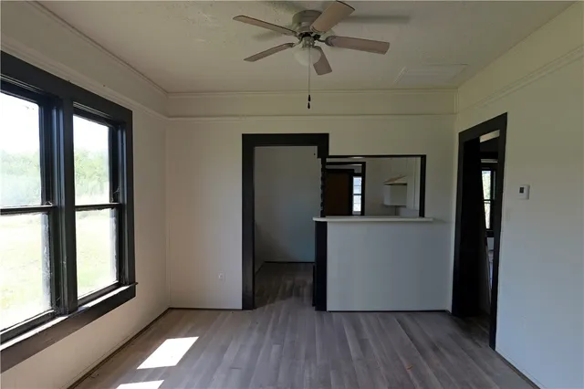 a view of empty room with wooden floor and fan