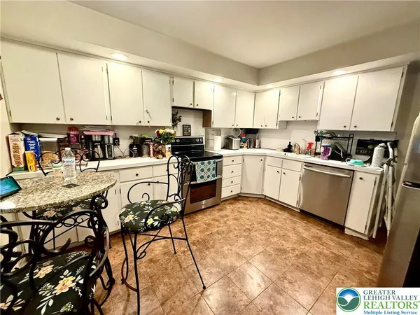 a kitchen with stainless steel appliances a sink a stove a refrigerator cabinets and a window