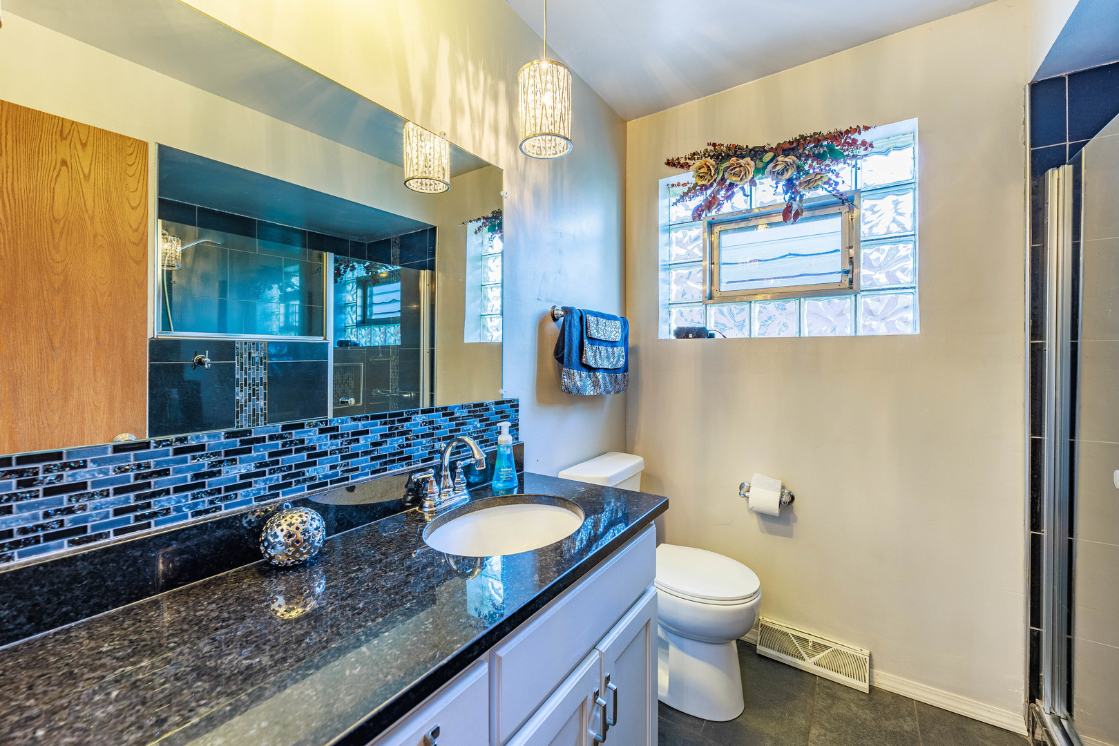 491 Escanaba Avenue Calumet City, IL 60409 - Photo 21 of 43 a bathroom with a granite countertop sink a toilet a mirror and shower