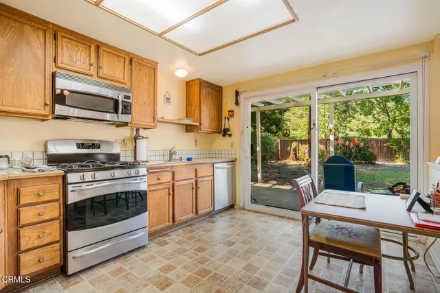 a kitchen with stainless steel appliances granite countertop a stove top oven a sink dishwasher a dining table and chairs with wooden floor