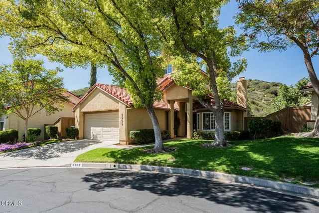 a front view of a house with a garden and trees